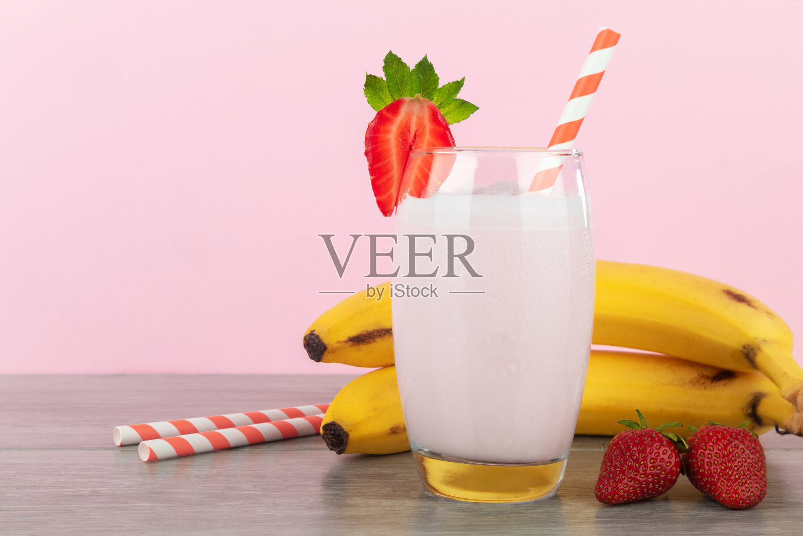 香蕉奶昔配上粉色背景的新鲜草莓。照片摄影图片