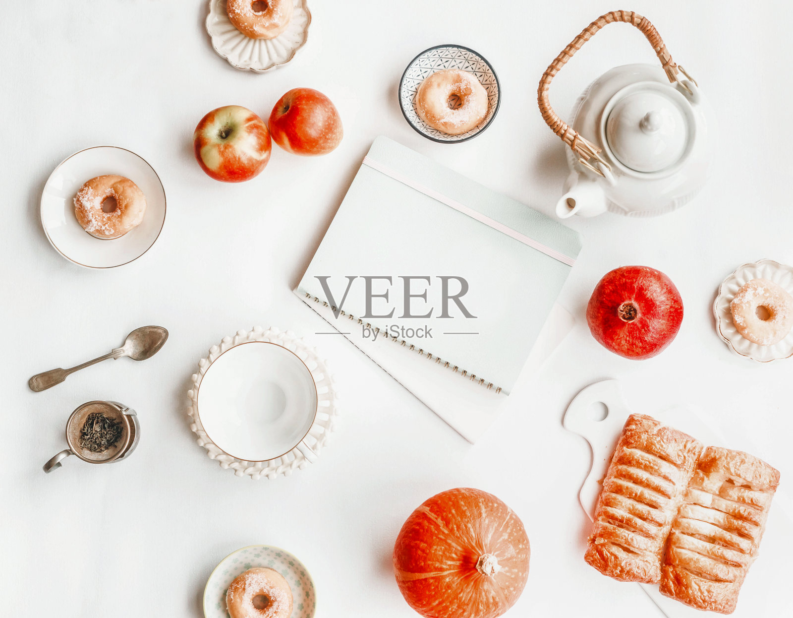 舒适的秋天静物组成与茶具，南瓜，甜甜圈和糕点在白色的背景。照片摄影图片