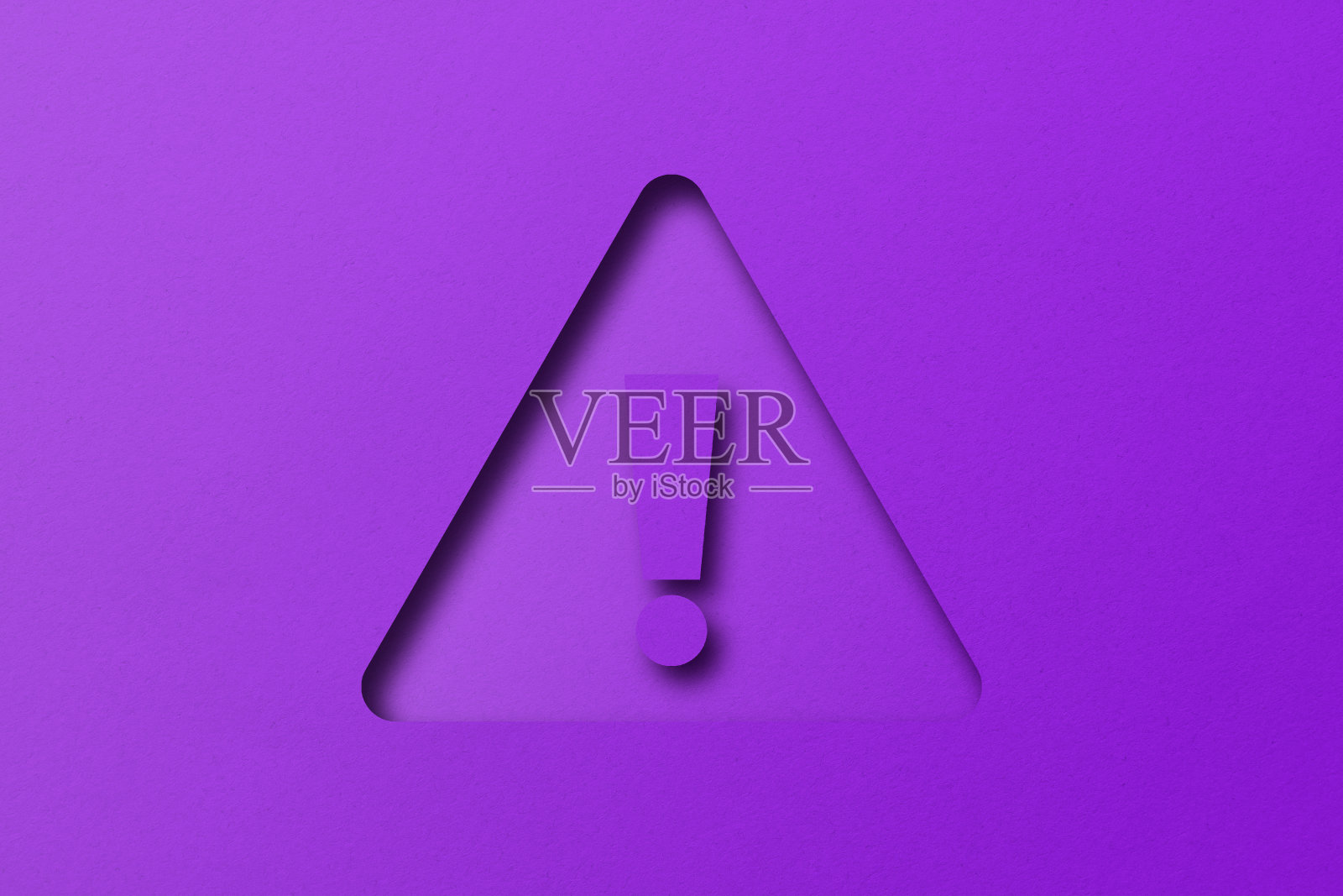 紫色的纸打孔成感叹号的形状。警告标志设置在紫色纸背景上照片摄影图片