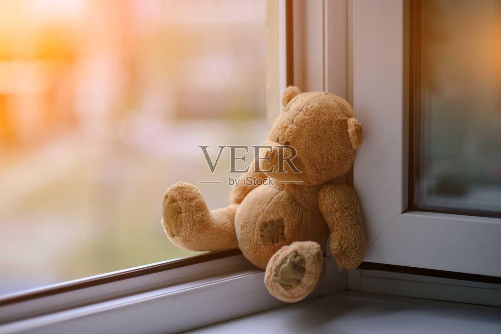 小熊的毛绒玩具坐在开着的窗户边。与孩子的概念事故。照片摄影图片
