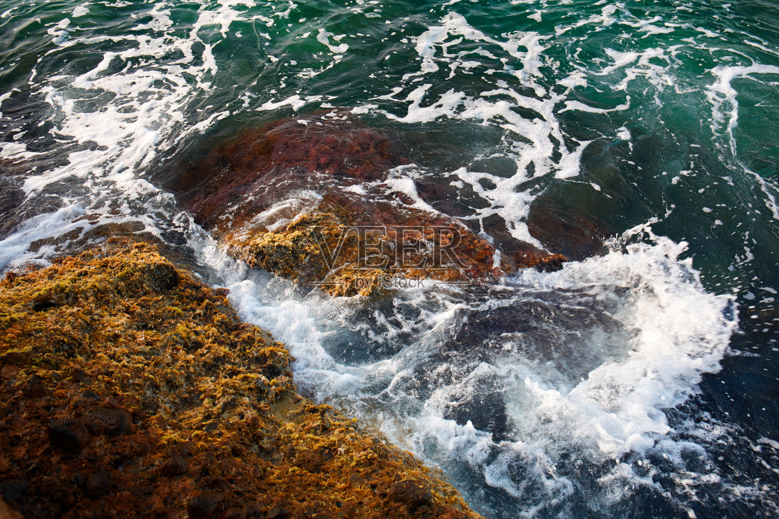 鸟瞰图，海浪冲击着海滩上的岩石，海水呈绿松石色。海岸线上令人惊叹的岩石悬崖海景。鸟瞰海浪和梦幻般的岩石海岸。地中海。照片摄影图片