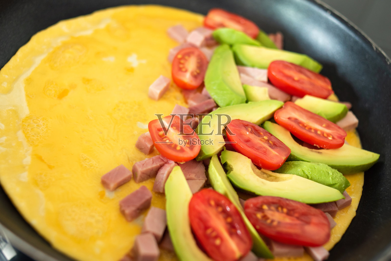 煎锅煎蛋，配火腿和新鲜蔬菜。照片摄影图片