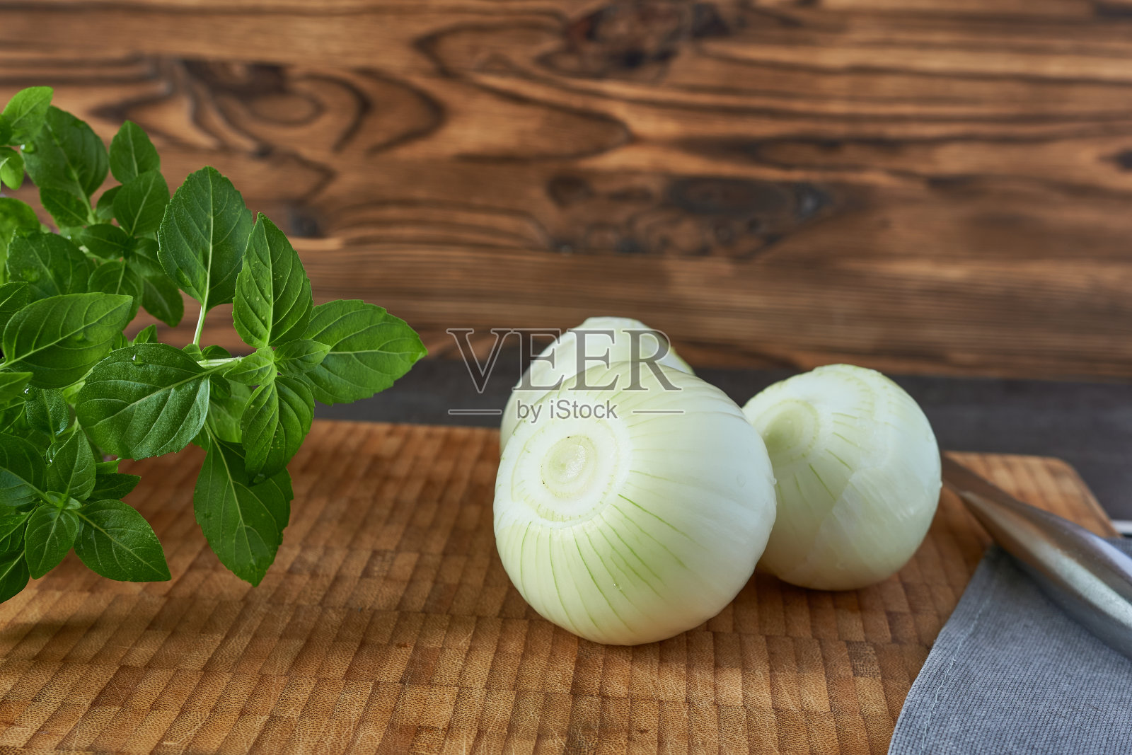 洋葱和罗勒放在砧板上，用刀放在木制背景上。照片摄影图片