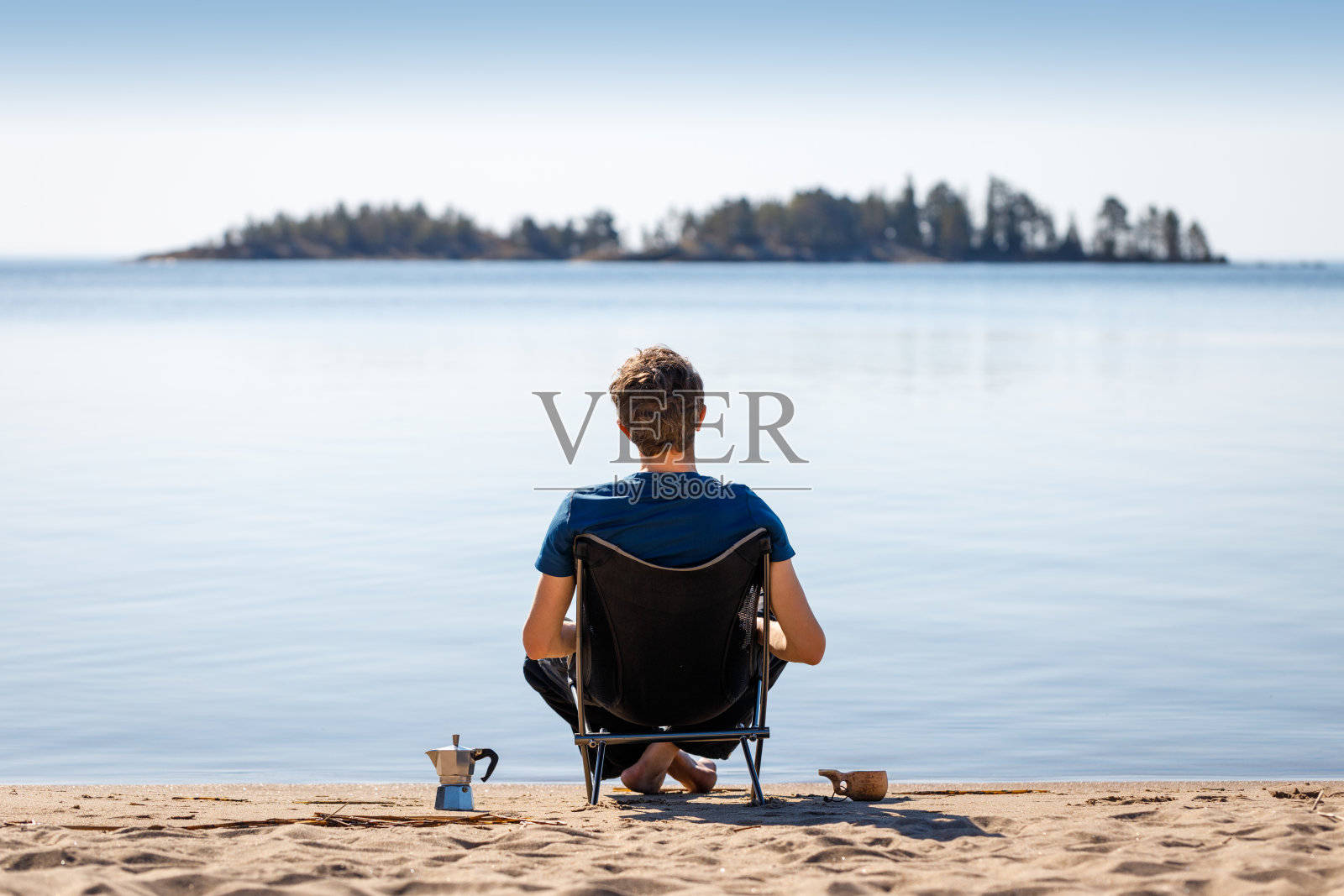 坐在海边露营椅上沉思的人。照片摄影图片