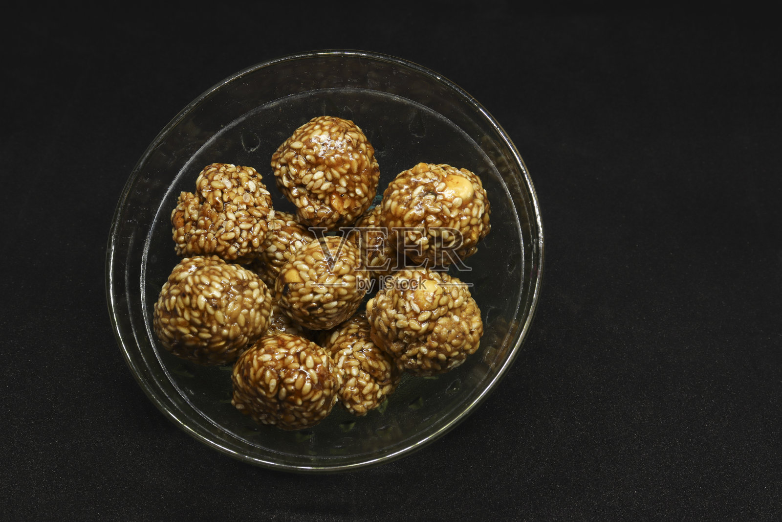 甜芝麻球放在杯子里。黑色背景照片摄影图片