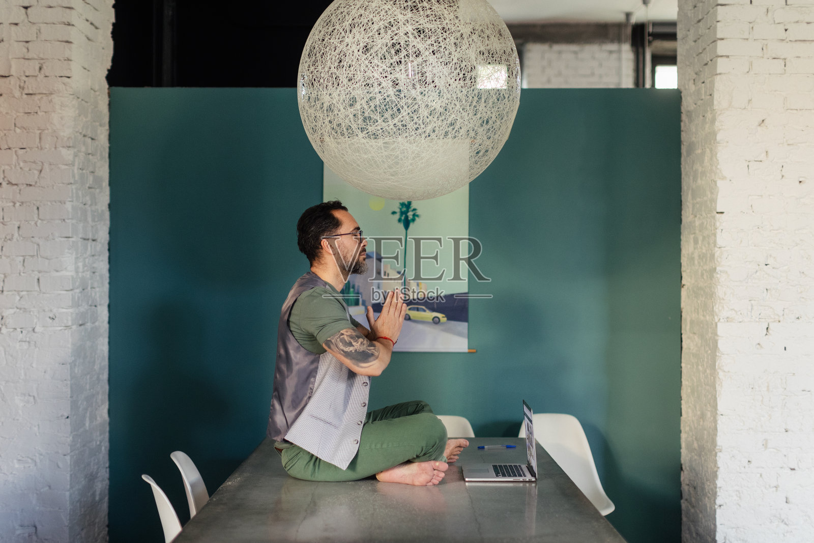 一个年轻人坐在办公室里冥想。照片摄影图片