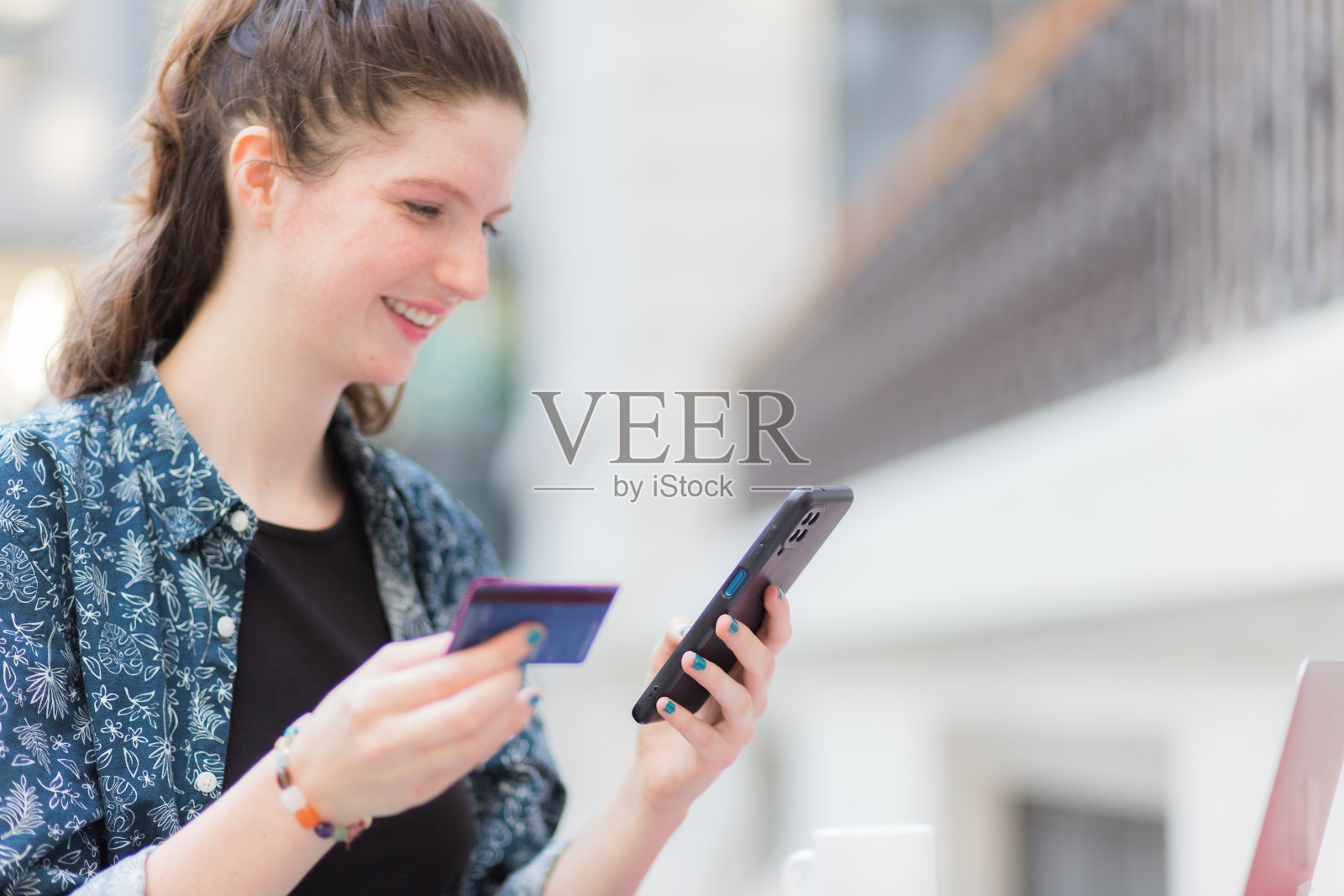 快乐的年轻女子使用信用卡和智能手机，在线支付的概念照片摄影图片