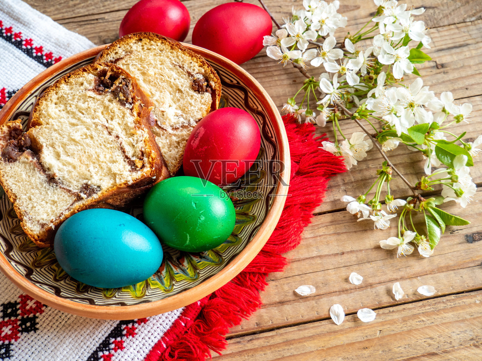 厨房桌子上的红色复活节彩蛋和科佐纳克切片，上面放着鲜花照片摄影图片