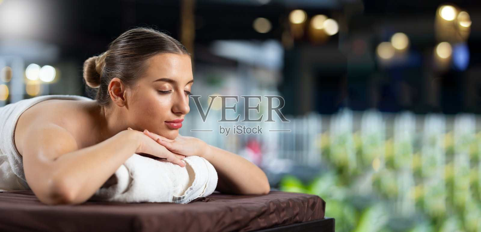 面部护理及护肤理念。快乐美丽的白人年轻女子闭上眼睛，放松在美容水疗和健康中心照片摄影图片