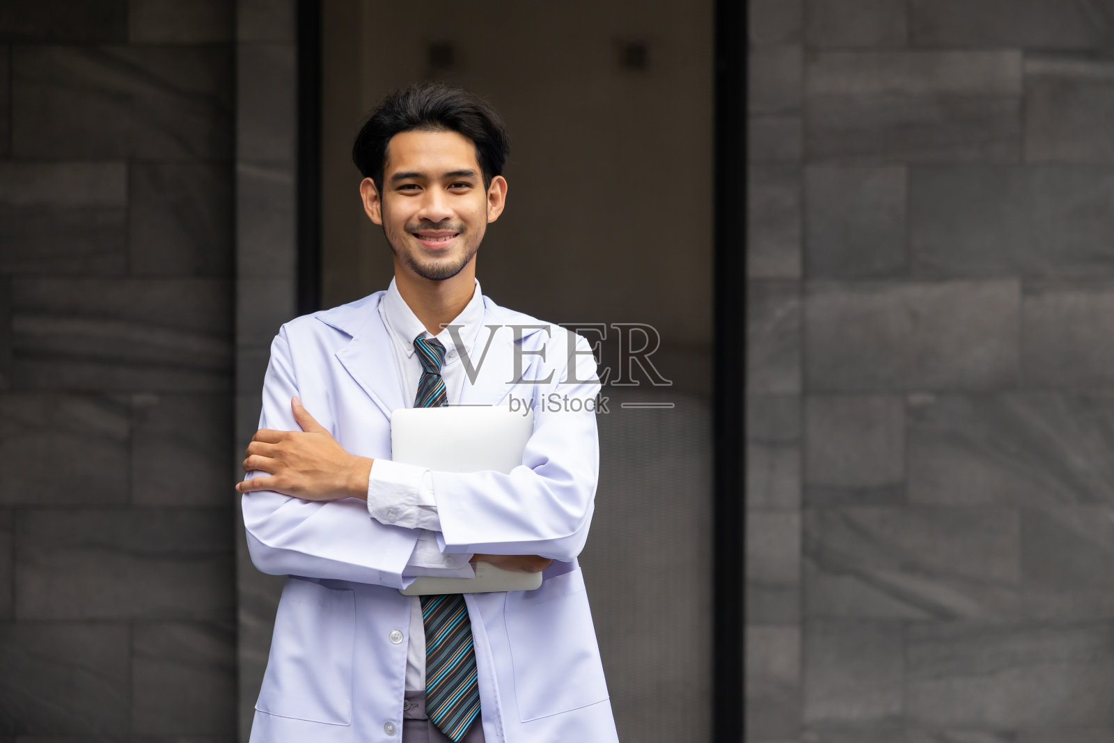 快乐的亚洲年轻医生摆姿势，微笑着看着镜头。医疗保健和医药照片摄影图片