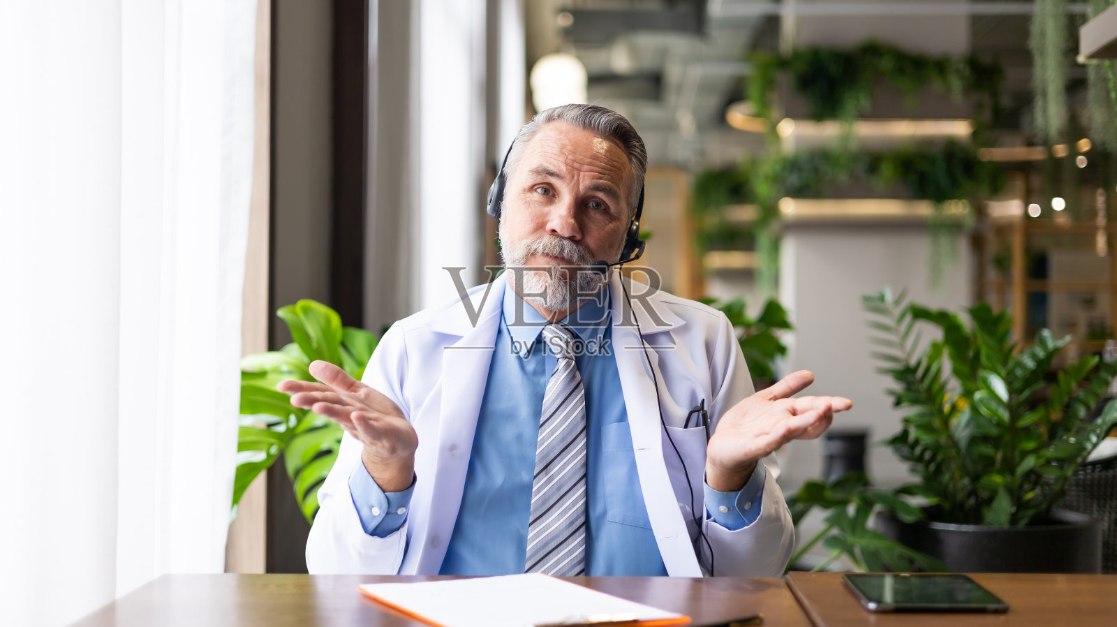 看着镜头。资深白种人医生在线视频电话会议在笔记本电脑上咨询病人。医生在线咨询和远程医疗照片摄影图片
