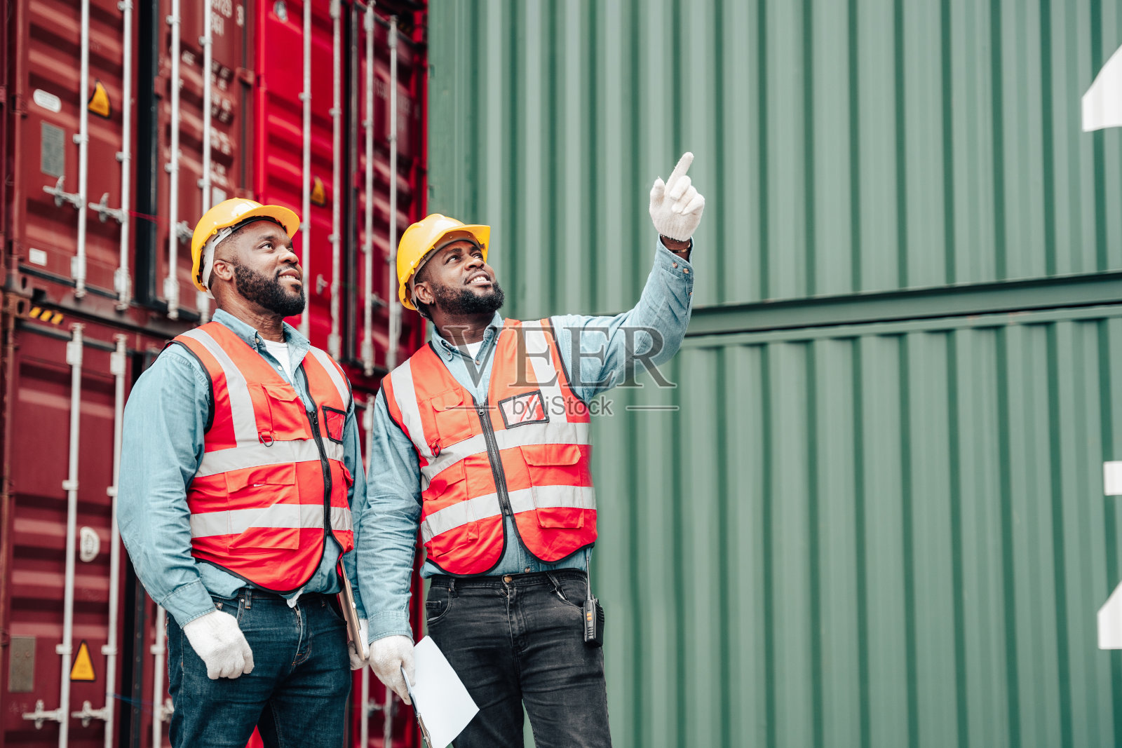 在一个堆满集装箱的港口，工人正在向领班报告集装箱的情况。照片摄影图片