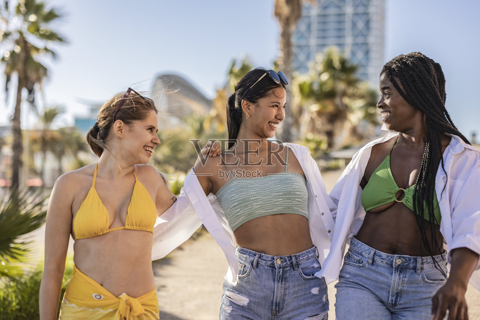 沙滩拥抱，多种族女性朋友开心就友情团聚假期为暑假相聚。自由、和平、蓝天和乐趣照片摄影图片