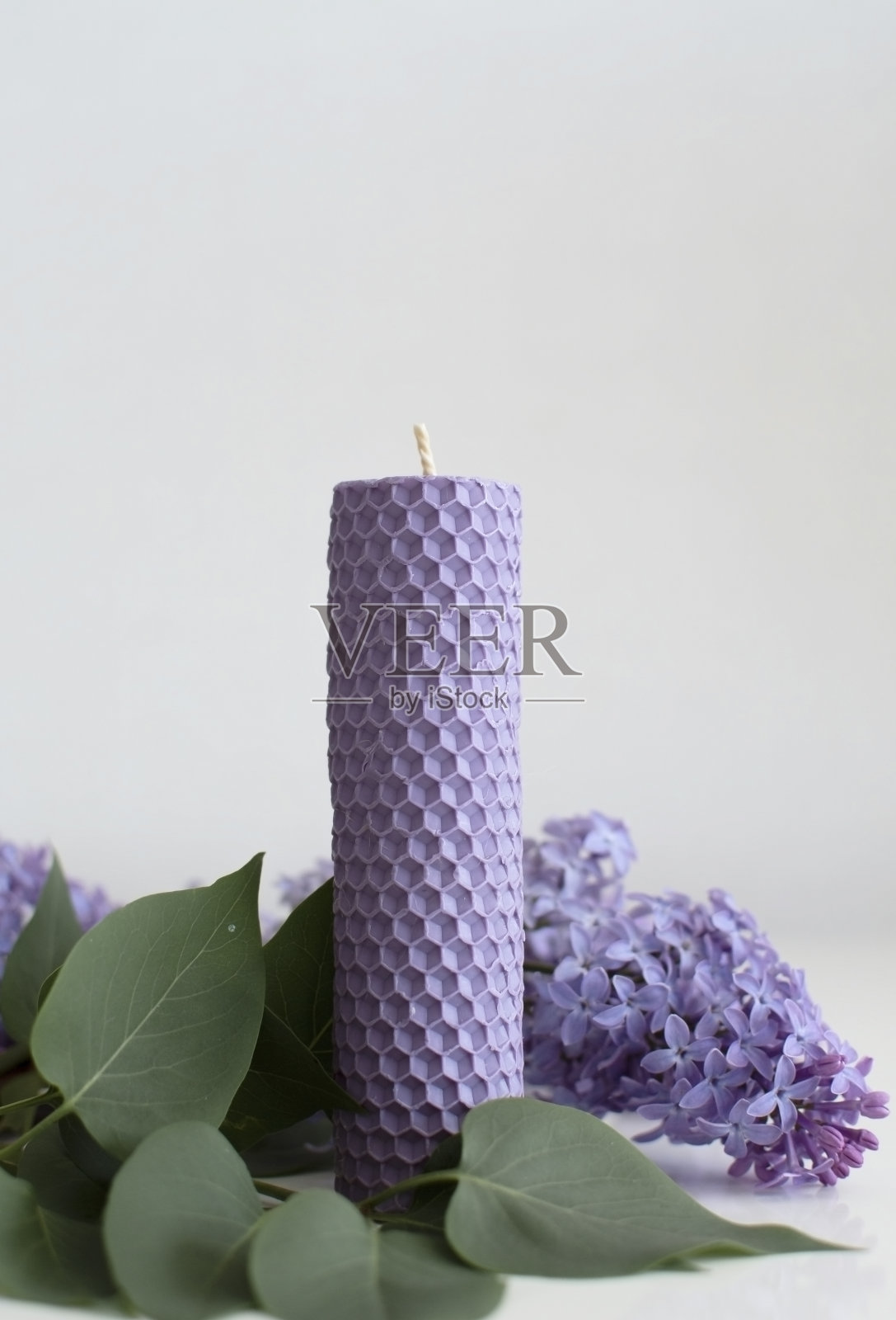 手工香薰蜡烛。一丛紫丁香和一支薰衣草蜡烛。垂直的照片。照片摄影图片