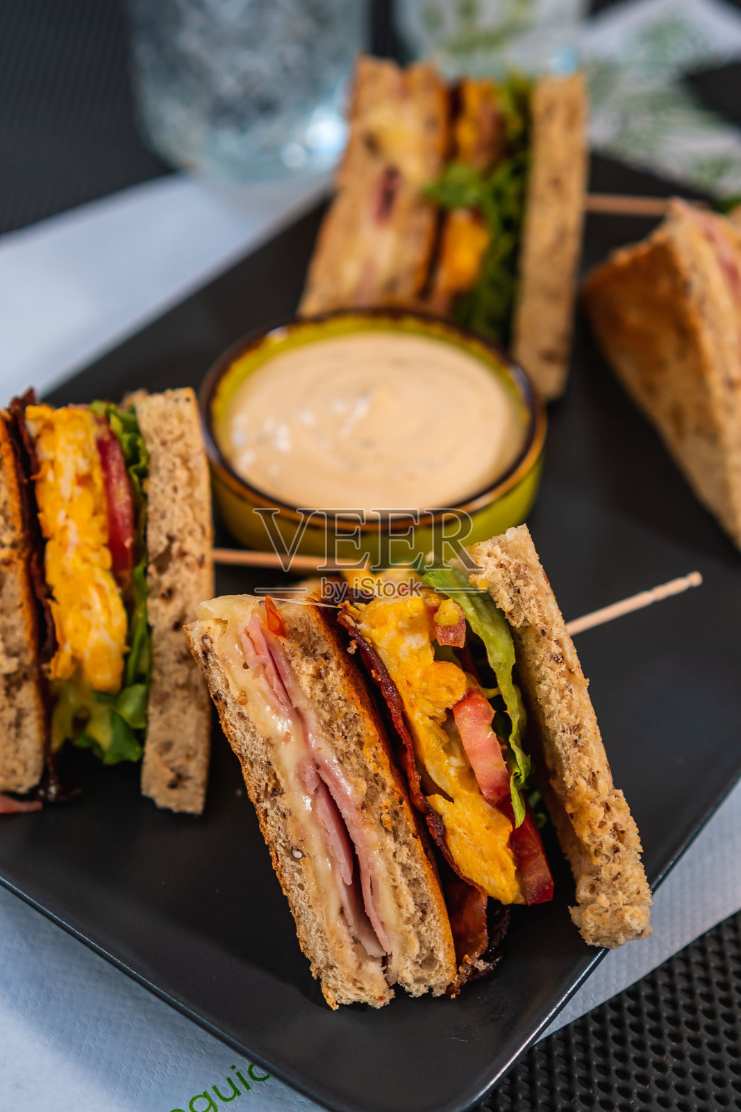 一个三明治放在黑色盘子里，旁边是蘸酱照片摄影图片