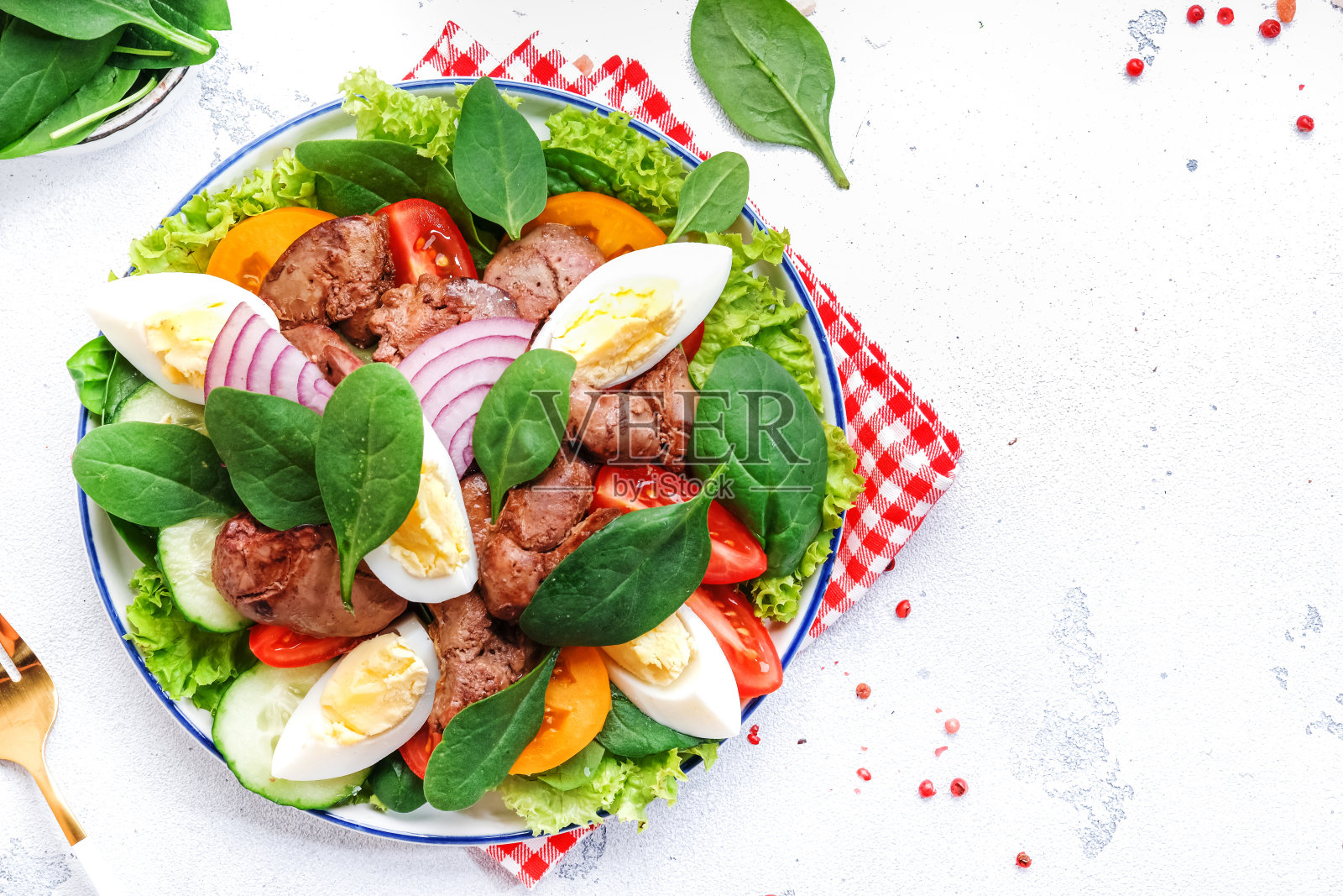 配烤鸡肝、红番茄、黄瓜、水煮蛋、生菜和菠菜的沙拉。白色厨房餐桌背景，俯视图照片摄影图片