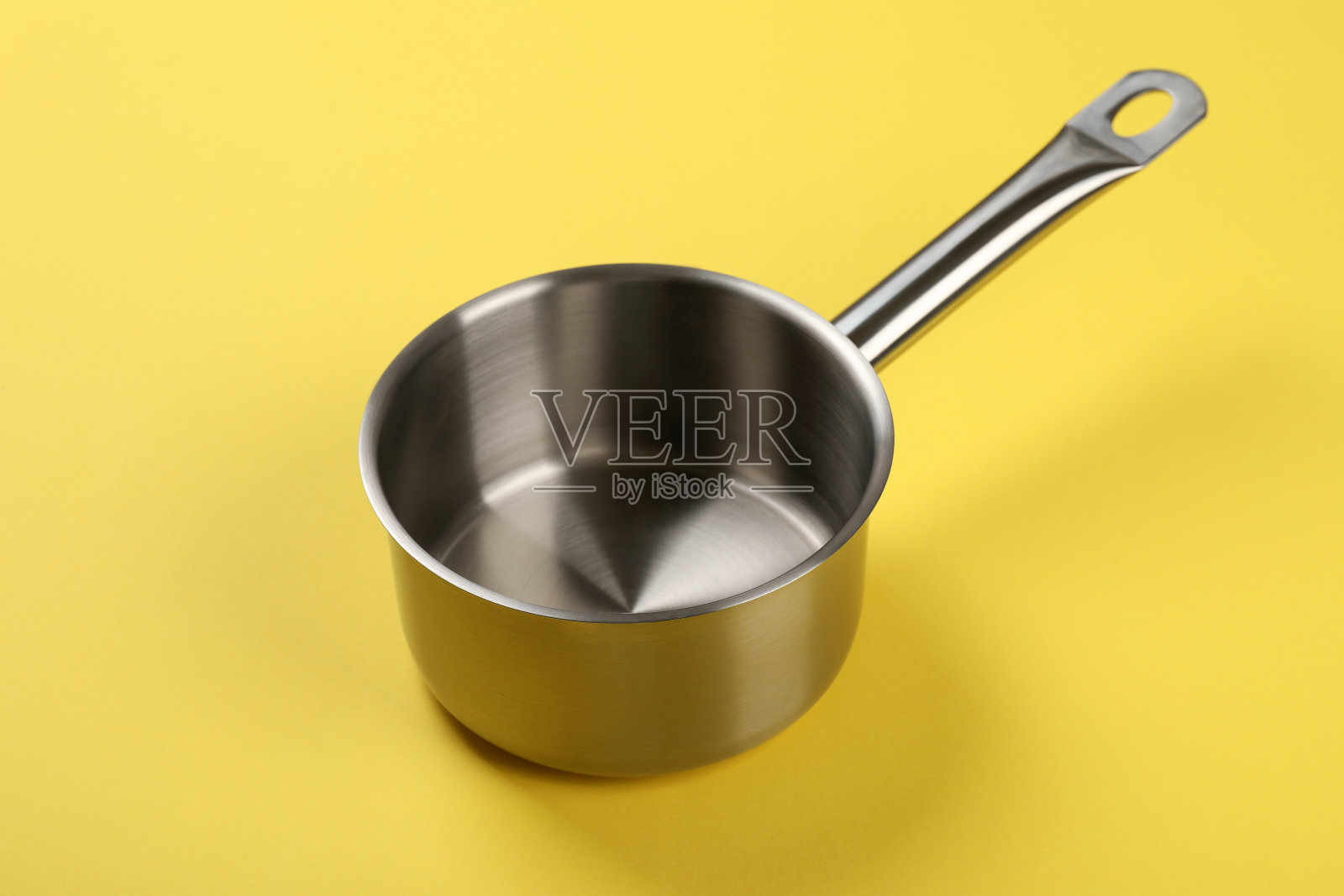 黄色背景上的金属空碗，特写照片摄影图片