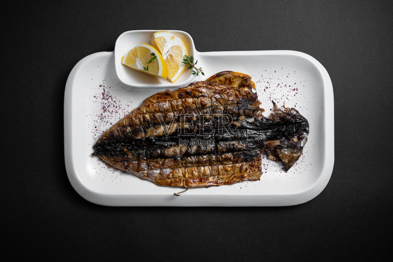 黑色背景的白色盘子上的柠檬烤鲭鱼的俯视图照片摄影图片