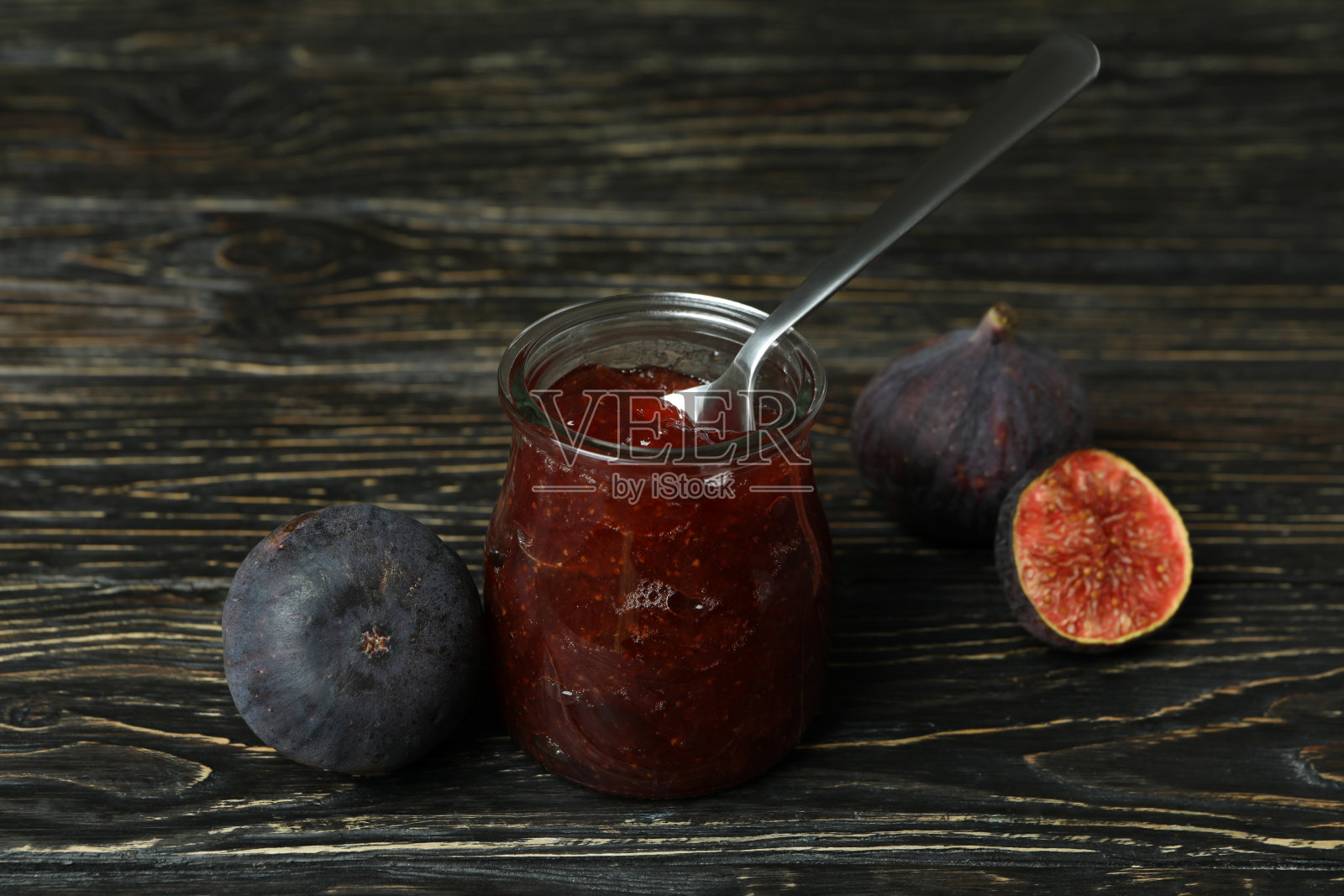 罐子里放无花果酱和勺子，原料放在木制背景上照片摄影图片