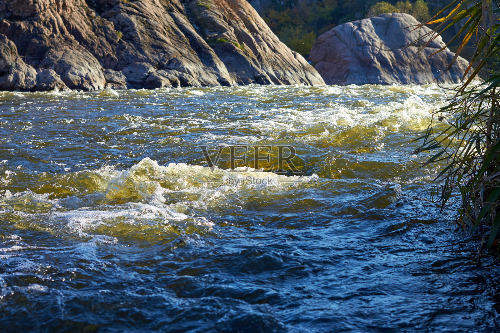 在秋天的荒野中，山间的河流湍急地沿着岩石的河岸流淌。海浪、浪花、泡沫和峭壁照片摄影图片