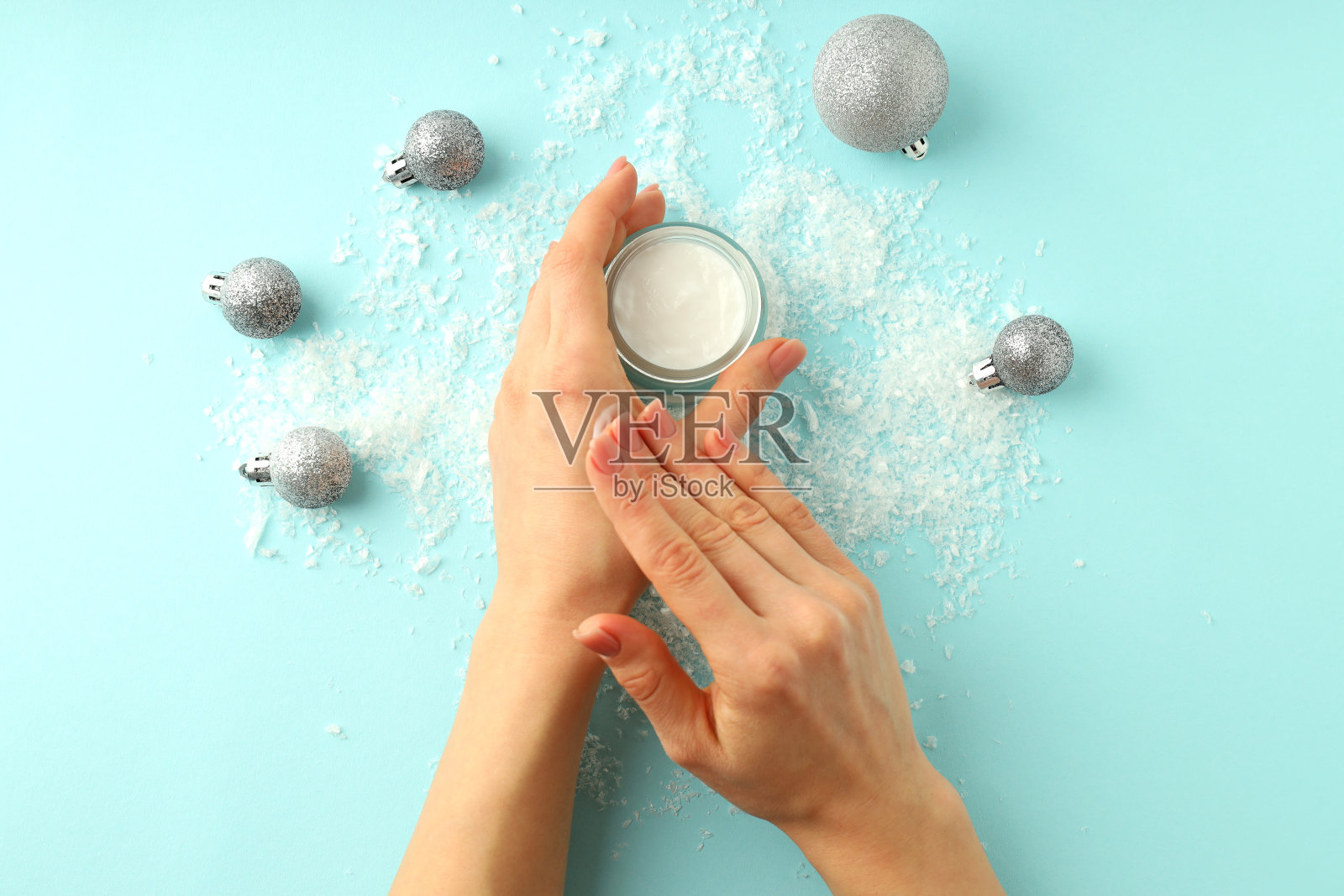 冬季化妆概念，女性双手在蓝色背景上涂抹奶油照片摄影图片