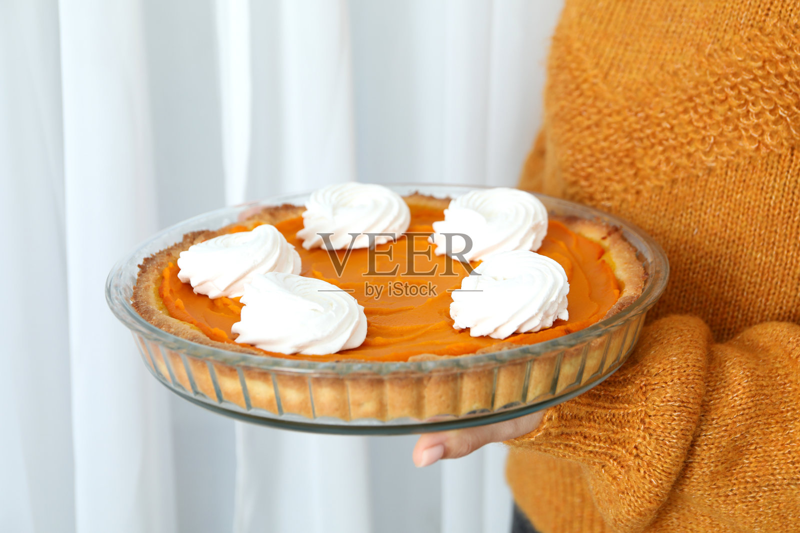 女人手里拿着南瓜派，近距离看照片摄影图片