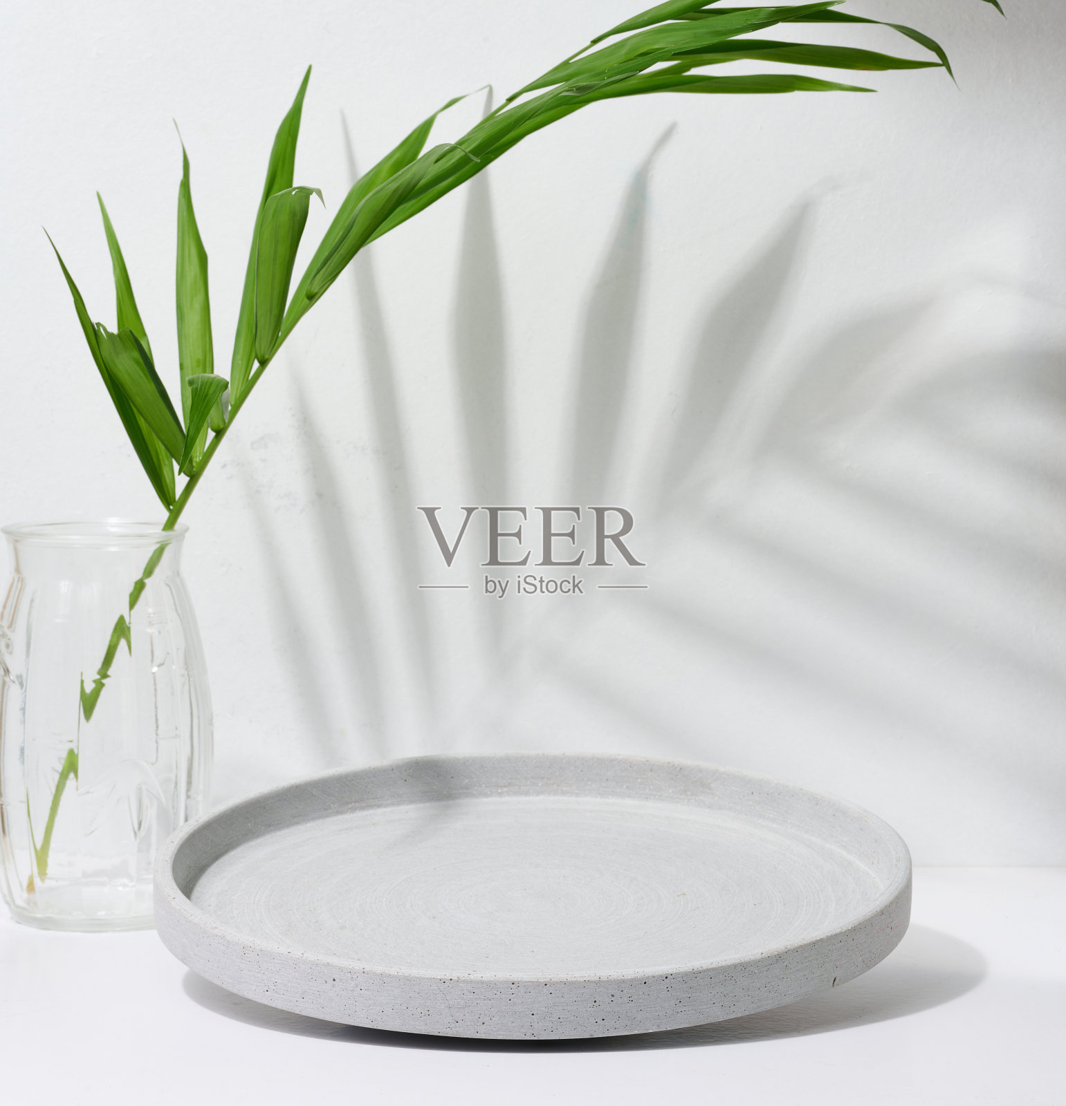 灰色的空装饰板和白色背景上绿色棕榈叶的玻璃花瓶，产品和化妆品展示舞台照片摄影图片