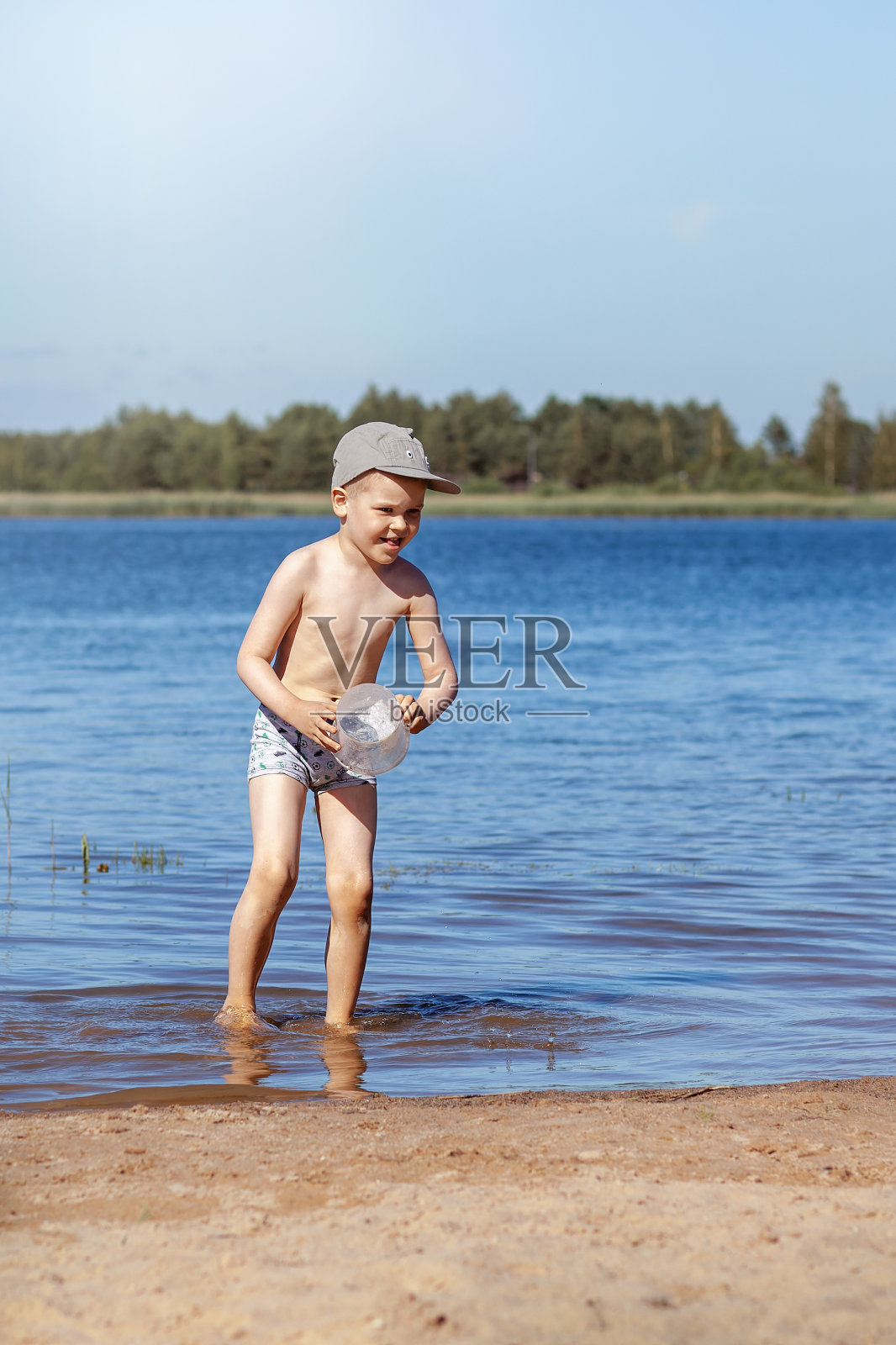 一个三岁的小男孩在森林湖里洗澡。怕水。垂直方向照片摄影图片