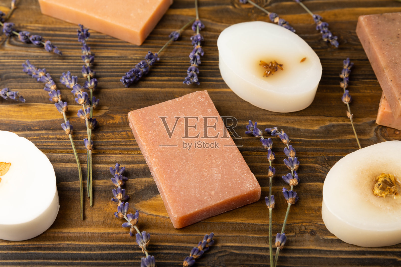天然薰衣草香皂与薰衣草花在一个棕色的木制背景。手工肥皂。含有精油的化妆品。水疗产品。文本空间。平的。照片摄影图片