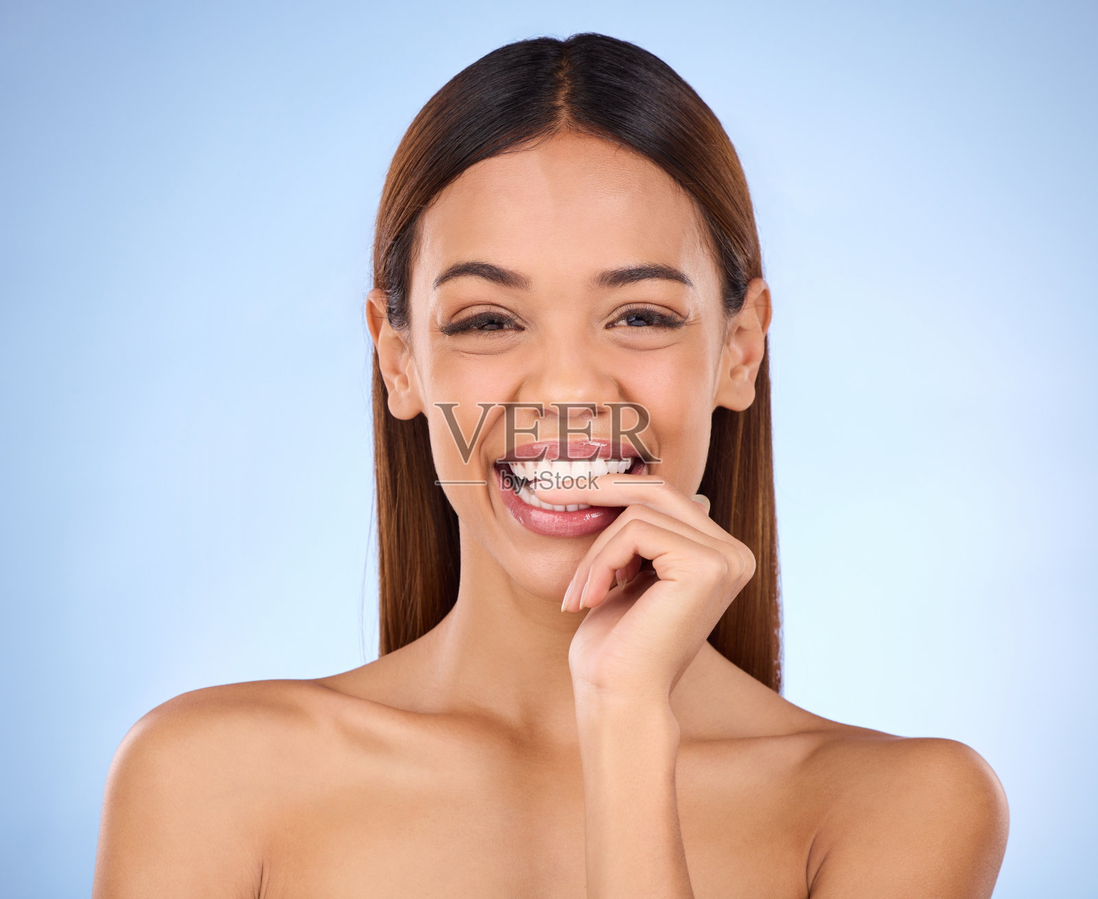 美容，女人和咬手指的肖像，为皮肤护理皮肤科化妆品工作室。女性模特人在蓝色的背景下自我护理，面部光泽和健康或清洁的皮肤带着微笑照片摄影图片