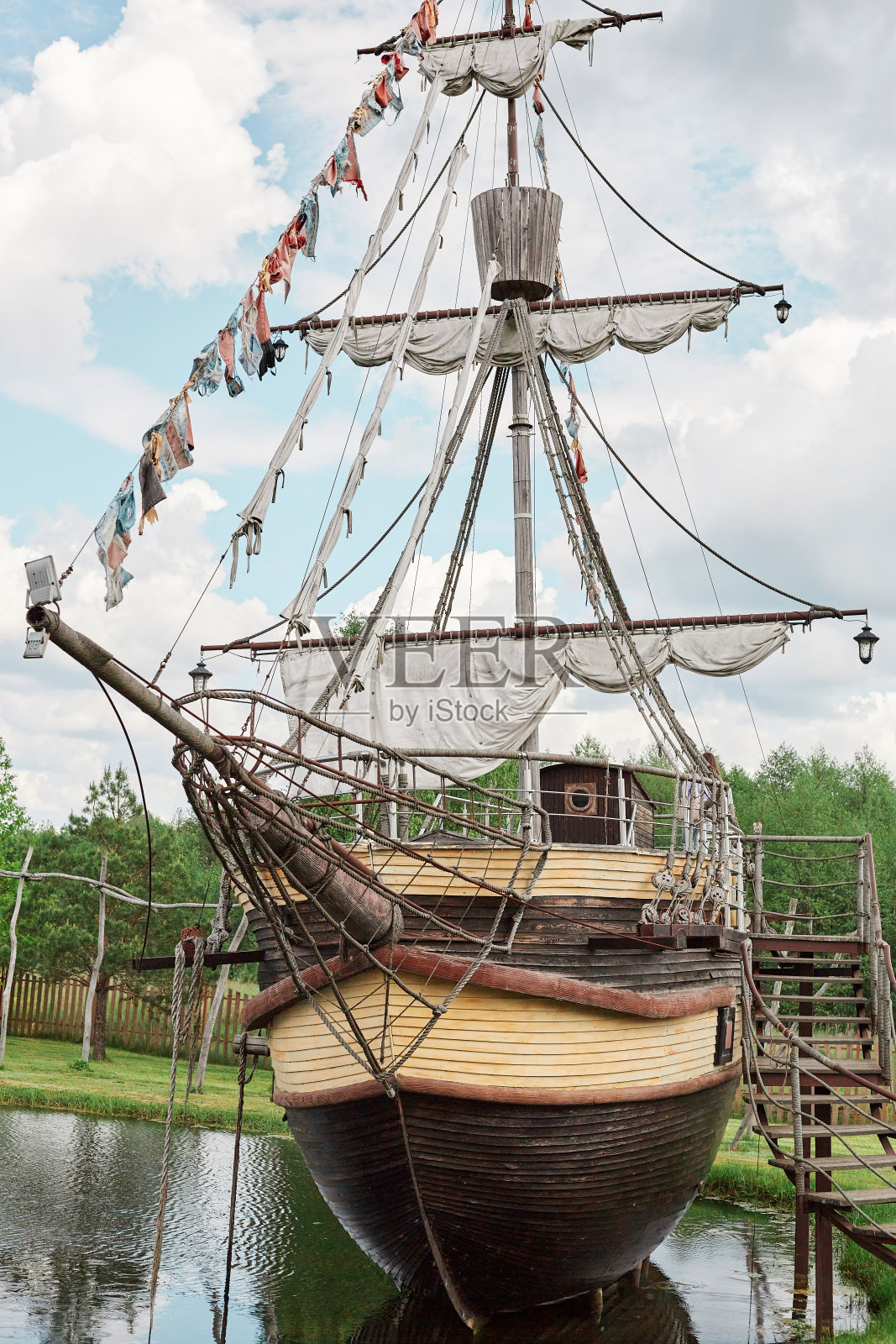 在靠近森林的河岸或湖边的港口的大船，带着风帆游览新地方的帆船。照片摄影图片