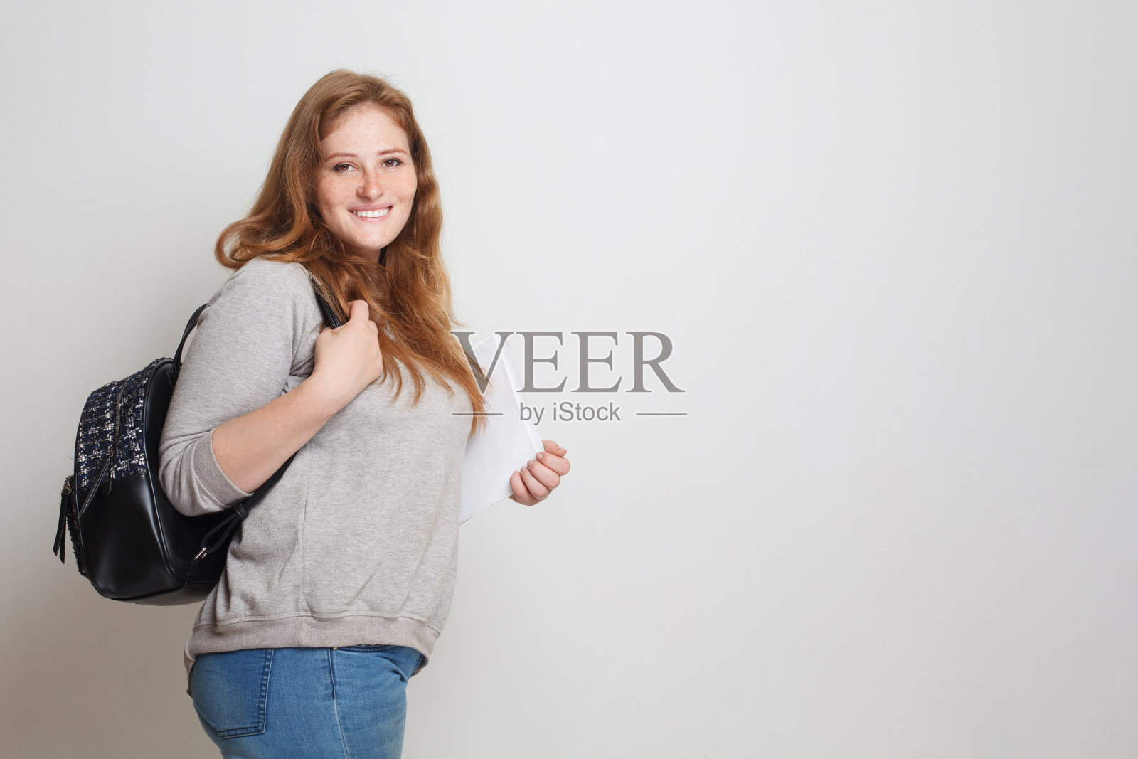 快乐的女学生站在白色的工作室墙上横幅的背景照片摄影图片