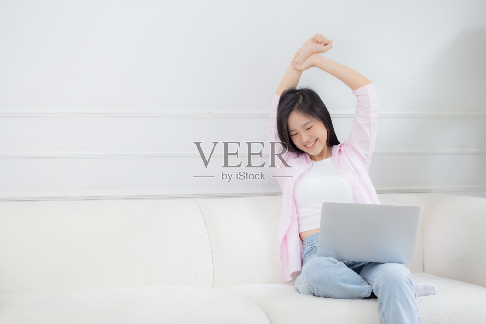 漂亮的年轻亚洲女商人坐在沙发上，在家工作，休息时在家里的客厅里伸展手臂放松，女人是自由职业者，在笔记本电脑上工作，商业理念。照片摄影图片