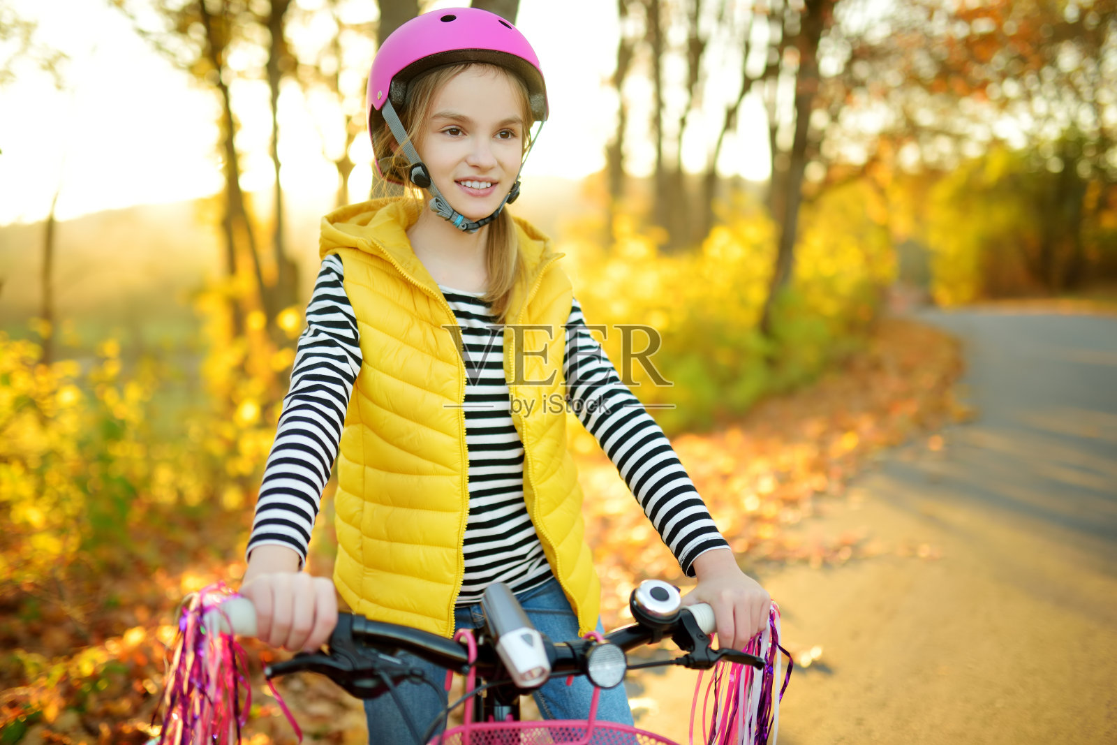 在一个阳光明媚的秋日，可爱的小女孩在城市公园骑自行车。积极的家庭休闲与孩子。照片摄影图片