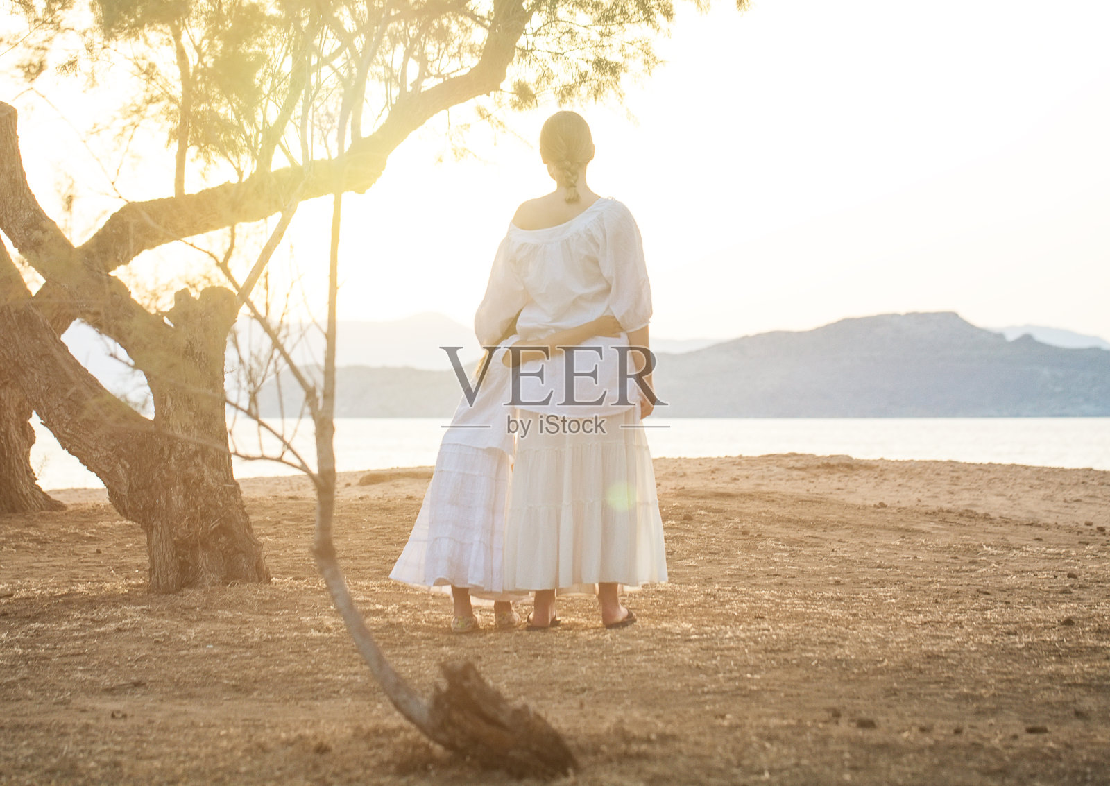 穿着白色衣服的漂亮姐妹，孩子和十几岁的女孩在公园里拥抱着，背靠着站在一起照片摄影图片