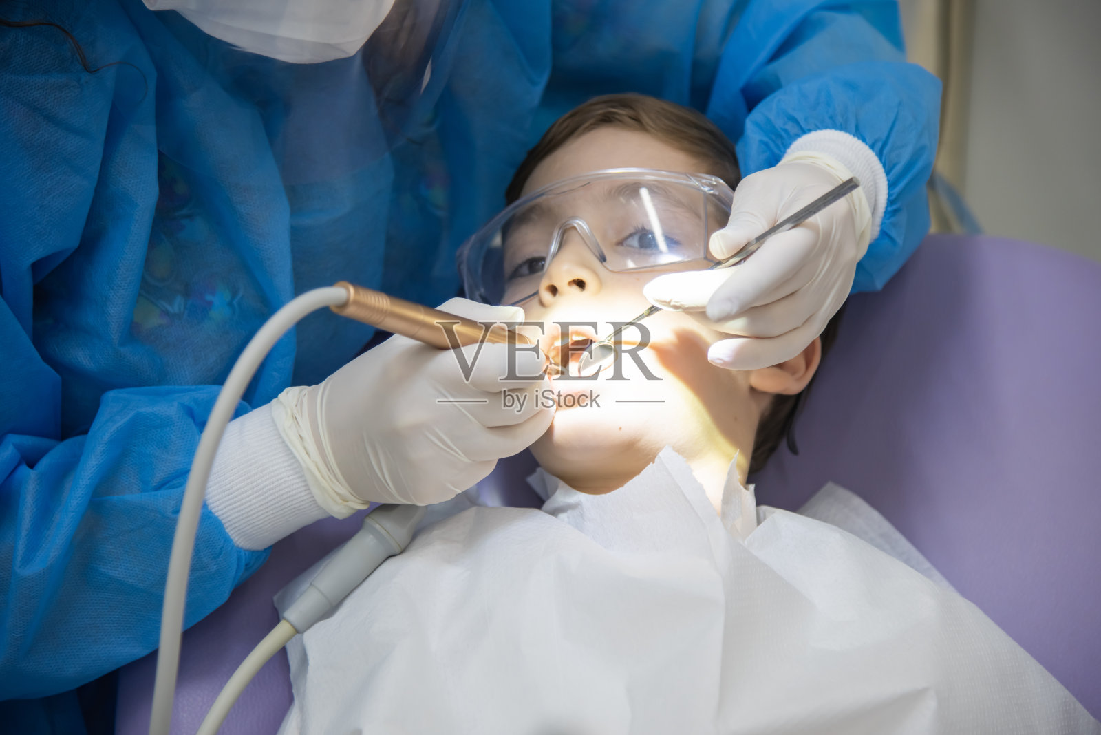 牙医坐在牙医椅上检查孩子的牙齿照片摄影图片