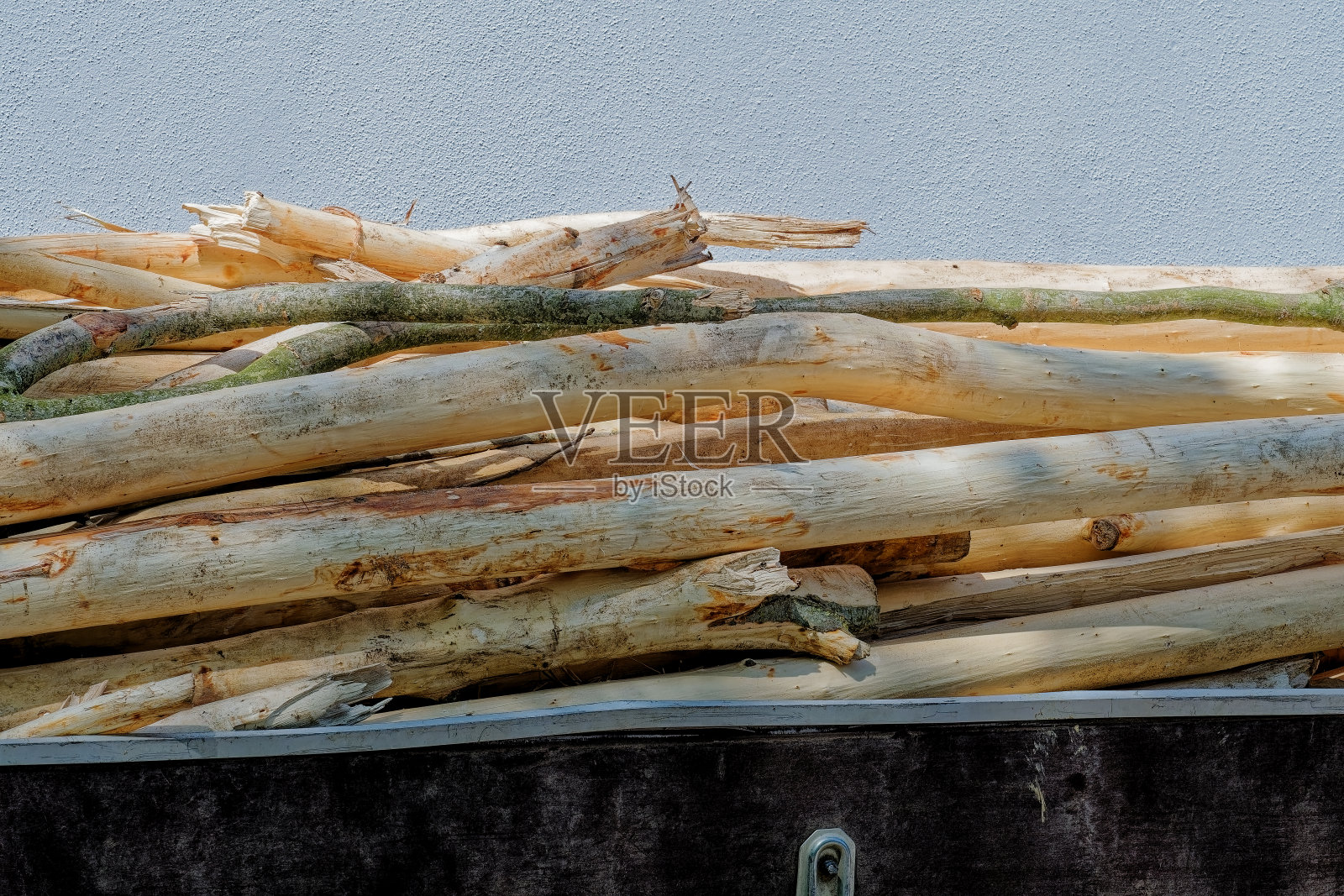 砍下来的树枝放在一辆金属手推车里。照片摄影图片