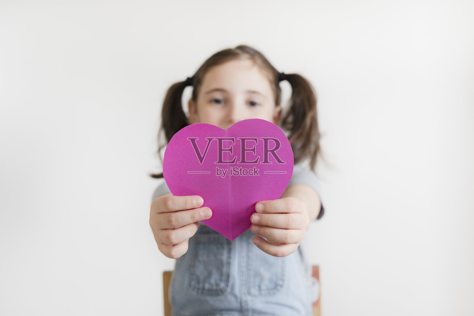 在白色背景上拿着心形物的小女孩照片摄影图片