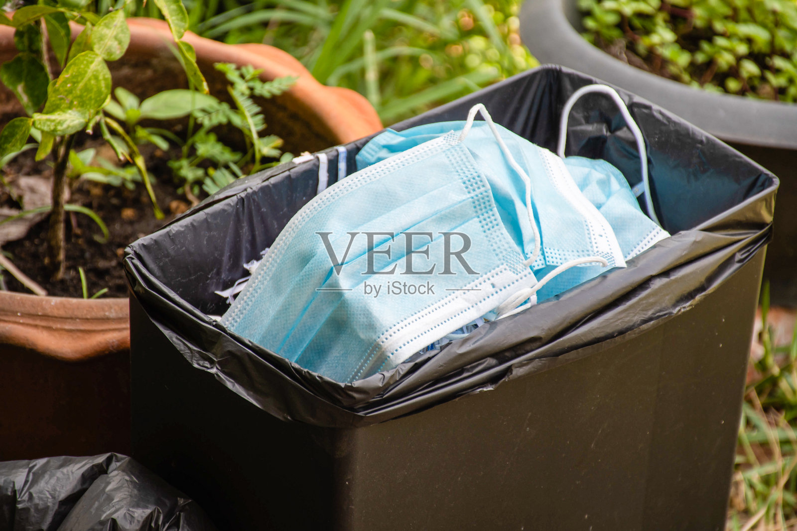 绿色口罩可以保护Covid-19。许多口罩被扔进了垃圾桶。危险的冠状病毒。医用口罩用于防护，可与口罩一对一使用。照片摄影图片