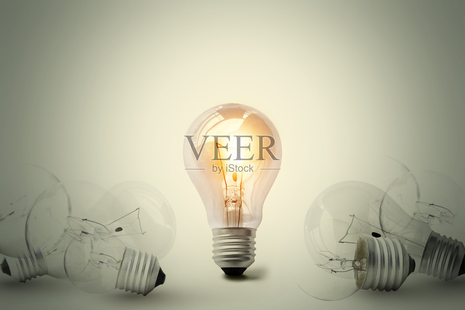 在许多不亮的灯泡之间的一个发光的灯泡。杰出的概念。概念上的不同思维或领导力。照片摄影图片