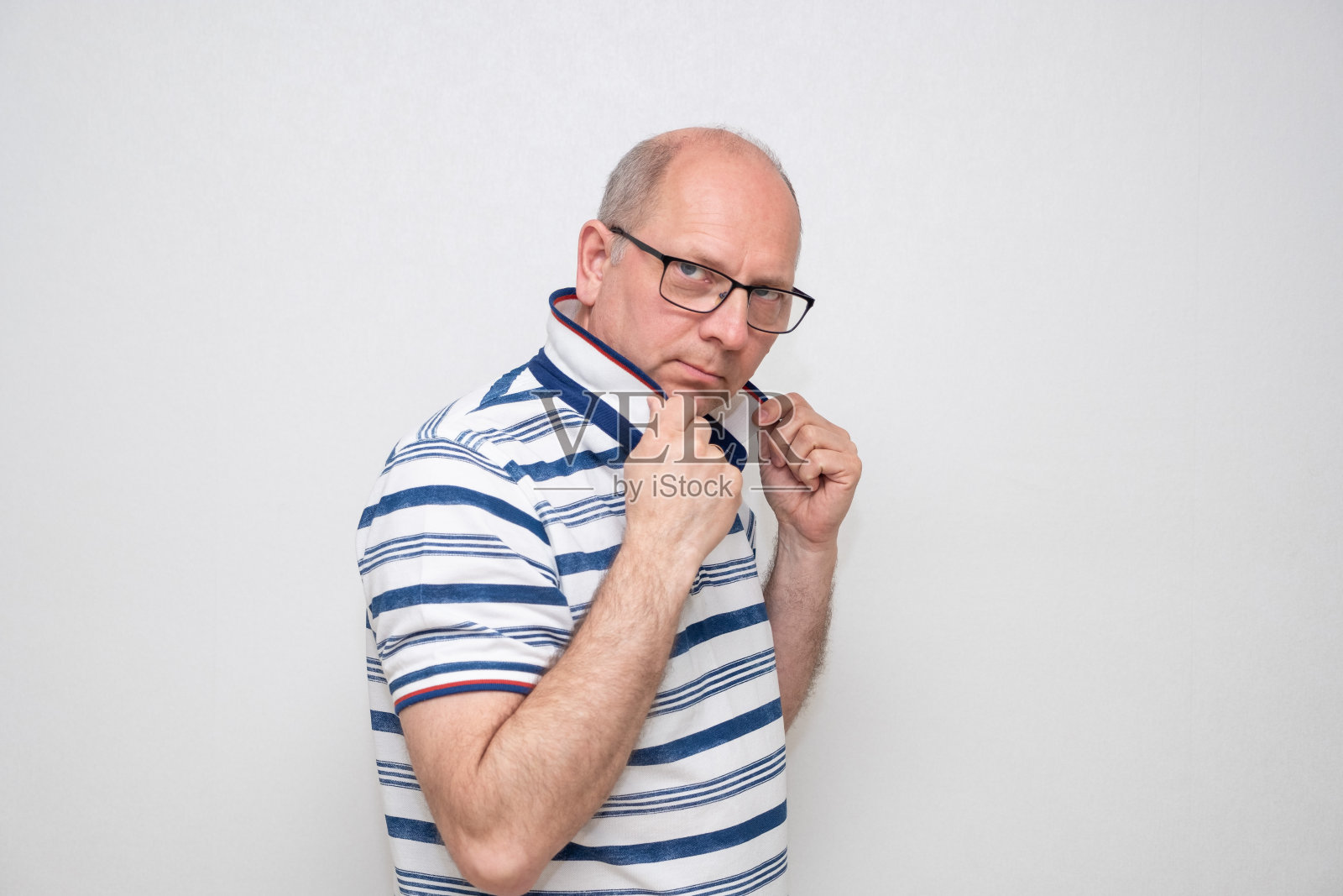 白人男子，50岁，灰色背景，穿着浅色衬衫，戴着眼镜，看着镜头。一系列的情绪。照片摄影图片