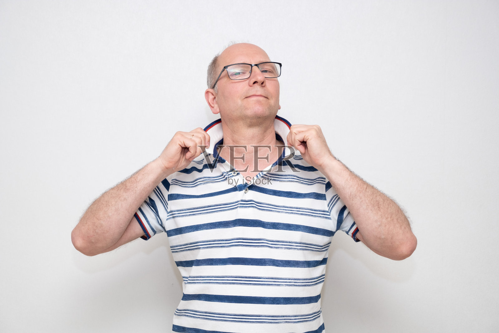 白人男子，50岁，灰色背景，穿着浅色衬衫，戴着眼镜，看着镜头。一系列的情绪。照片摄影图片