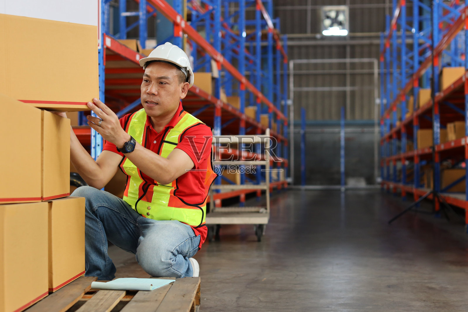 带安全帽和反光夹克的仓库工人检查清单或控制大箱包装，以交付生产库存和零售仓库物流，配送中心的库存照片摄影图片
