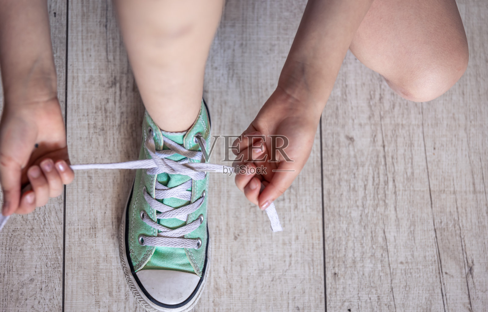 孩子成功地系好鞋带，紧系在脚上。照片摄影图片