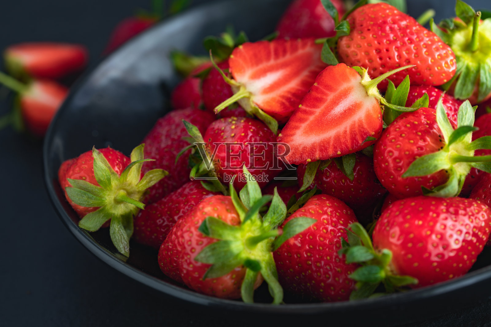 在暗石桌上的碗里放着成熟的新鲜草莓，拉近了复制空间照片摄影图片