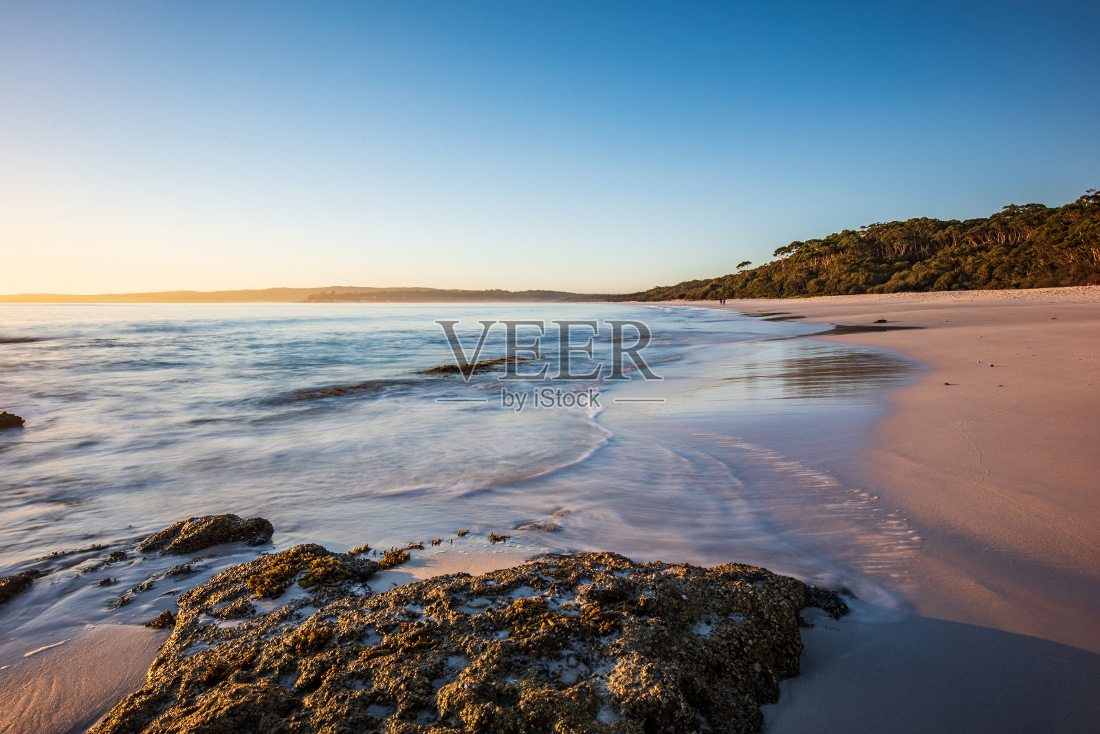 海浪轻轻冲刷岩石的海景，蓝天和金色的海滩照片摄影图片