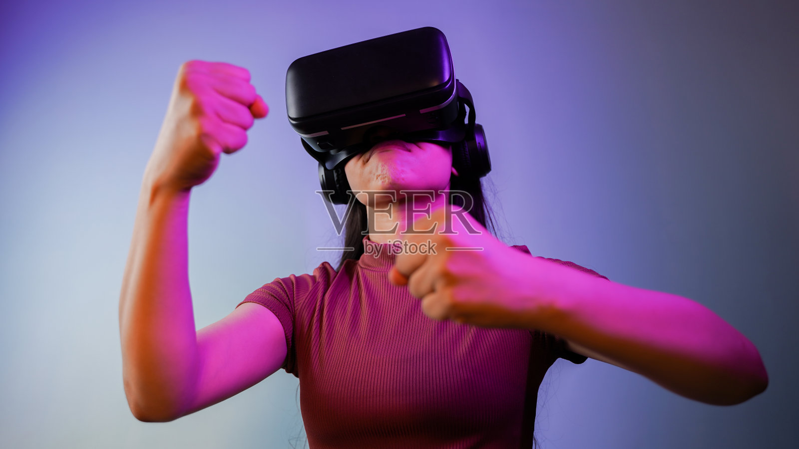 年轻的亚洲印度女子紧握拳头，戴着虚拟现实耳机，女孩戴着vr眼镜概念工作室肖像照片摄影图片