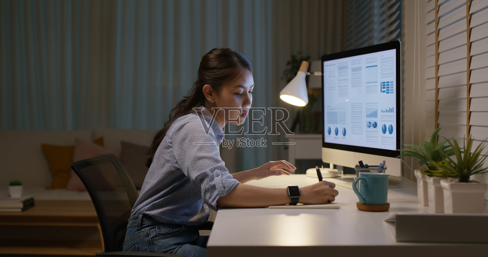 年轻的亚洲女性人才劳动力人们快乐工作努力深夜忙碌坐在家里办公桌旁阅读销售计划在台式电脑上在线报告数据在混合工作空间为工人重新培训提高技能课程。照片摄影图片