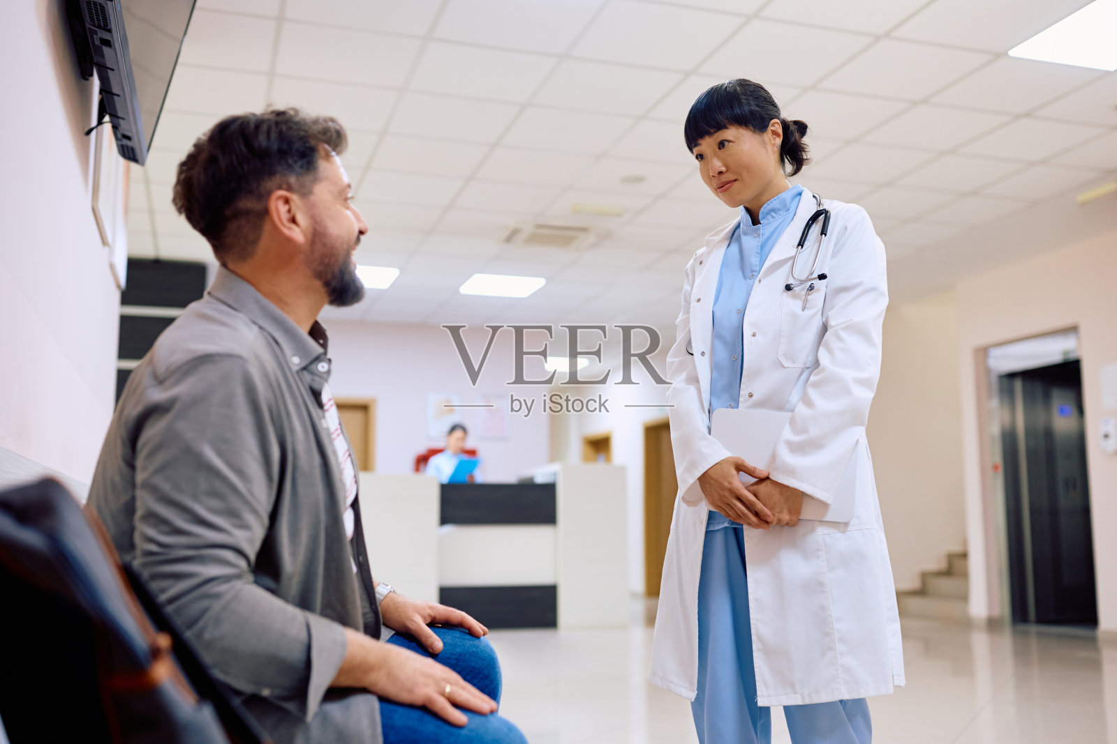 日本女医生在诊所候诊室与病人交谈。照片摄影图片