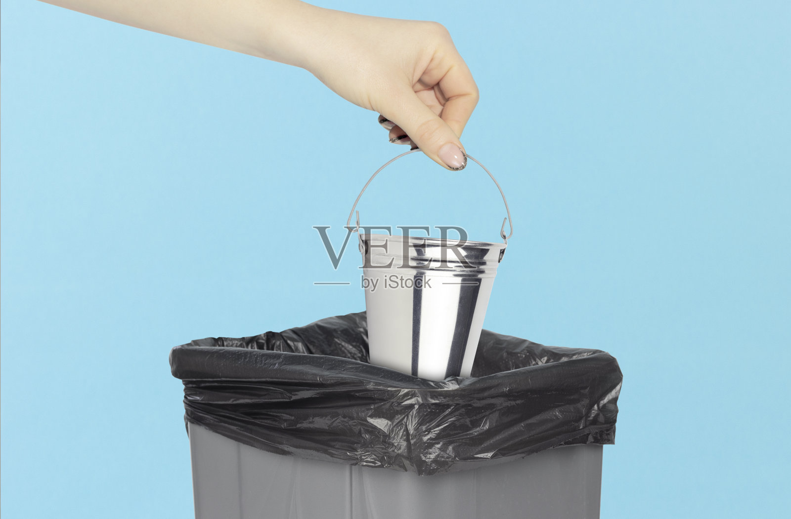 把水桶扔进垃圾桶，水桶小在垃圾桶前的手里照片摄影图片